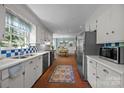 Bright kitchen featuring white cabinetry, stainless steel appliances, checkerboard backsplash, and brick flooring at 5510 Sardis Rd, Charlotte, NC 28270