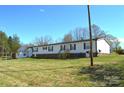 Rear view of the house showcasing the spacious yard, stairs to the back door, and additional storage buildings at 648 Dobson Farm Rd, Statesville, NC 28625