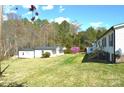 Large grassy backyard with mature trees and several outbuildings, offering ample space and privacy at 648 Dobson Farm Rd, Statesville, NC 28625