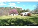 View of backyard outbuildings and shed with mature trees and lawn at 648 Dobson Farm Rd, Statesville, NC 28625