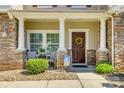 Inviting front porch with stone pillars, seating, and a decorative wreath on the front door at 722 Sandy Green Ct, Fort Mill, SC 29715