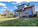Angle view of a two-story home boasting blue siding, a covered porch with a yellow door, and a well-manicured lawn at 126 E Henderson St, Salisbury, NC 28144