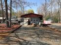 Exterior shot of the home featuring a red awning, boats, and gravel parking surrounded by mature trees at 149 Deer Park Rd # D26/27, Mount Gilead, NC 27306