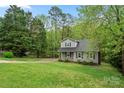 Two-story home with gray siding and black shutters on a spacious green lawn surrounded by mature trees at 2717 Stockwood Dr, Gastonia, NC 28056
