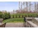 Landscaped backyard with well-maintained green lawn, mature trees, stone-paved patio, and fence at 423 Granite Lake Ct, Denver, NC 28037