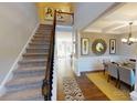 Inviting foyer with staircase leading to dining room featuring elegant decor and ample natural light at 7016 Butternut Oak Ter, Huntersville, NC 28214