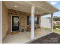 Inviting covered front porch featuring a seating area and stylish brick columns at 10773 Sapphire Trl, Davidson, NC 28036