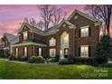 Charming brick two-story home with manicured lawn in the evening at 16123 Chiltern Ln, Huntersville, NC 28078
