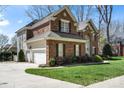 Side view of a brick two-story home with attached garages and green lawn at 16123 Chiltern Ln, Huntersville, NC 28078