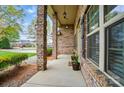 Covered porch with brick pillars, outdoor lanterns, flower pots, and neutral mulch at 5032 Eagles Crest Ln, Gastonia, NC 28056