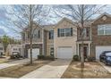 View of townhome row featuring neutral siding, stone accents, attached garages, and tidy landscaping at 9035 Bradstreet Commons Way, Charlotte, NC 28215