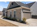 Exterior view of home with stone veneer, gray siding, and a convenient two-car garage with an extended driveway at 12709 Messenger Row, Huntersville, NC 28078