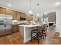 Eat-in kitchen features a kitchen island with seating and stainless steel appliances next to an open living space at 2018 Puddle Pond Rd, Indian Trail, NC 28079