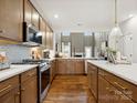 The kitchen features sleek stainless steel appliances, pristine white countertops, and elegant brown cabinetry at 2018 Puddle Pond Rd, Indian Trail, NC 28079