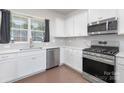 Modern kitchen featuring stainless steel appliances, white cabinetry, and neutral tile backsplash with natural light at 3013 Whipcord Dr, Waxhaw, NC 28173