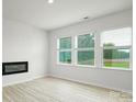 Living room featuring an electric fireplace, luxury vinyl plank flooring, and three large windows at 3052 Ora Smith Rd, Lincolnton, NC 28092