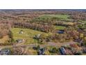 An aerial view captures the home and outbuildings on a vast parcel of land surrounded by a pond and beautiful forest at 3526 Harmony Hwy, Harmony, NC 28634