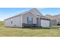This is an exterior view of a gray house, showcasing its side, garage, and well-maintained lawn at 3543 Cramer Creek Dr, Gastonia, NC 28056