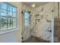 Beautiful primary bathroom featuring glass shower with marble style tiles and a window view at 3753 Capps Hill Dr, Charlotte, NC 28216