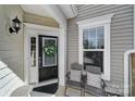 Welcoming front porch with neutral decor, features a stylish black door with wreath and comfortable seating area at 45008 Wigeon Ln # 101, Indian Land, SC 29707