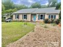 Inviting one-story home featuring a welcoming front yard and a charming turquoise front door at 7412 Broken Oak Ln, Charlotte, NC 28226