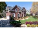 Beautiful brick home featuring a manicured lawn, mature trees, and a three-car garage at 880 Craigmont Nw Ln, Concord, NC 28027
