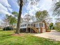 Expansive backyard with mature trees, deck, a ground-level patio, and garage access at 12011 Stoney Meadow Dr, Mint Hill, NC 28227