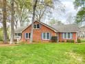 Charming brick home featuring a manicured lawn and complemented by vibrant blue shutters at 12011 Stoney Meadow Dr, Mint Hill, NC 28227