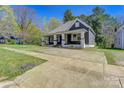 Exterior view of a quaint home showcasing a covered front porch and ample driveway space at 209 N Yadkin Ave, Spencer, NC 28159