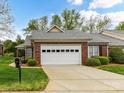 Brick home featuring a two-car garage with lush green grass and landscaping around the property at 3721 Oak View Ct, Matthews, NC 28105