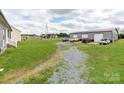 Rear view of the property showing a long gravel driveway leading to a detached garage and parking area at 514 Baucom Deese Rd, Monroe, NC 28110