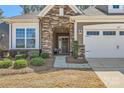 Close up showing stone facade, walkway and trimmed shrubs at entrance to home and two-car garage at 525 Cellini Pl, Mount Holly, NC 28120