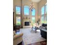Spacious living room features a fireplace, large windows, and a beautiful chandelier at 708 Ridgelake Dr, Weddington, NC 28104