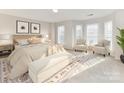 Sun-filled bedroom with neutral decor, a sitting area, and large windows at 7854 Springs Village Ln, Charlotte, NC 28226