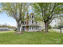 Stately two-story home with a rounded tower, lush lawn, and inviting wrap-around porch at 101 E Main St, Cleveland, NC 27013