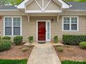 Welcoming entrance with a red front door, surrounded by lush greenery and framed by a paved walkway at 1018 Davant Ln, Charlotte, NC 28209