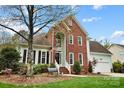Charming brick home boasting a lush front lawn, mature trees, and a welcoming entrance with an American flag at 1214 Foxfield Rd, Waxhaw, NC 28173