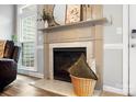 Cozy fireplace with a decorative mantel, flanked by a window and dark leather couch at 1214 Foxfield Rd, Waxhaw, NC 28173