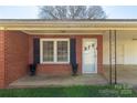 Covered front porch featuring a classic brick facade, black shutters, and decorative planters at 260 Trexler Ln, Rock Hill, SC 29732