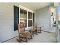 Inviting front porch featuring rocking chairs and a small table creating a cozy outdoor living space at 7116 Brookline Pl, Huntersville, NC 28078