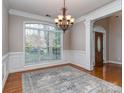 Spacious dining room with wainscoting, hardwood floors, large windows and modern chandelier at 1009 Summer Creste Dr, Indian Trail, NC 28079