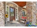 Inviting front porch with stone columns, a wooden bench, and a decorative sunflower accent at 176 Sunset Bay Dr, Troutman, NC 28166
