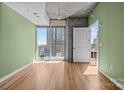 Bright living room featuring a private balcony with city views, hardwood floors, and a painted accent wall at 210 N Church St # 2305, Charlotte, NC 28202