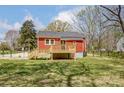 Rear view of a red home featuring a wooden deck overlooking the spacious green backyard at 50 Sixth St, York, SC 29745