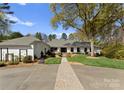 Charming single story home with a large front lawn, mature trees, and long brick walkway to the front door at 2015 Pellyn Wood Dr, Charlotte, NC 28226