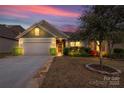 Charming single-story home featuring manicured landscaping, a two-car garage, and a welcoming entrance at dusk at 2035 Palace Way, Indian Land, SC 29707