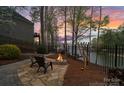 A stone patio with fire pit sits near a fence with lake views providing a serene and private outdoor space at 2228 Metcalf Dr, Sherrills Ford, NC 28673