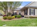 A stone home exterior with manicured lawn, shrubbery, and a cozy outdoor seating area at 744 Ledgestone Ct, Tega Cay, SC 29708