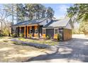Side view of an updated home boasting black brick, wood trim, metal roof and well maintained landscaping at 7816 Wallace Ln, Charlotte, NC 28212