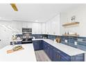 Modern kitchen features white upper cabinets and blue lower cabinets with quartz counters and stainless steel appliances at 7816 Wallace Ln, Charlotte, NC 28212